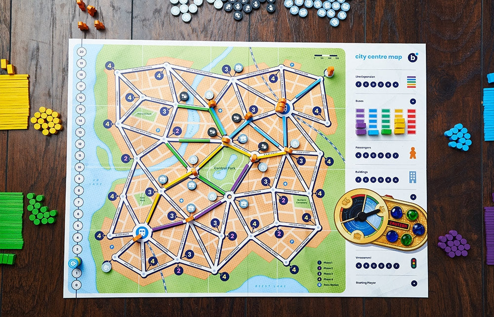 Bus: Complete Edition by Capstone Games is displayed on a wooden table, featuring tokens, player pieces, cards, and piles of green, yellow, blue, and purple wooden game pieces arranged around the board.