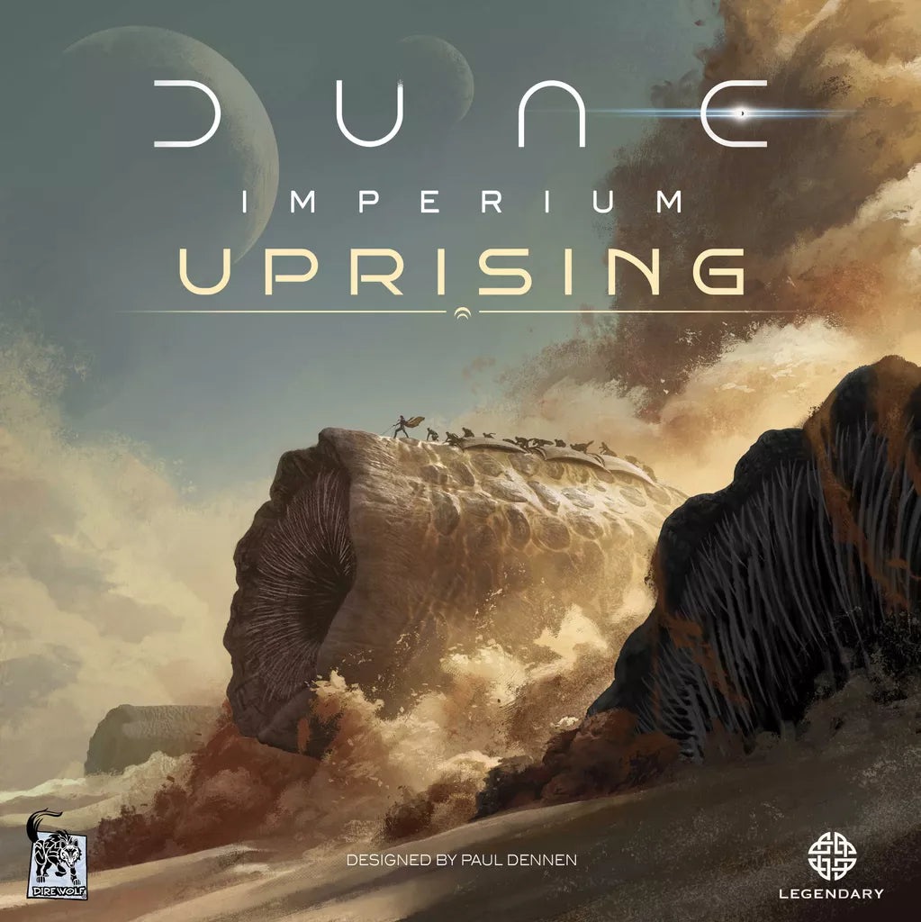 A giant sandworm rises under a dramatic sky as small figures stand on its back. The text "Dune: Imperium Uprising" by Dire Wolf appears, hinting at exciting deck-building and worker placement; logos are in the corners.