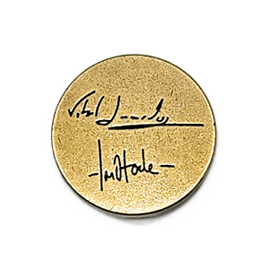 The Weather Machine: Metal Nobel Prize by Eagle-Gryphon Games is a round, gold-tone pin with two black signatures stacked vertically on a plain background.