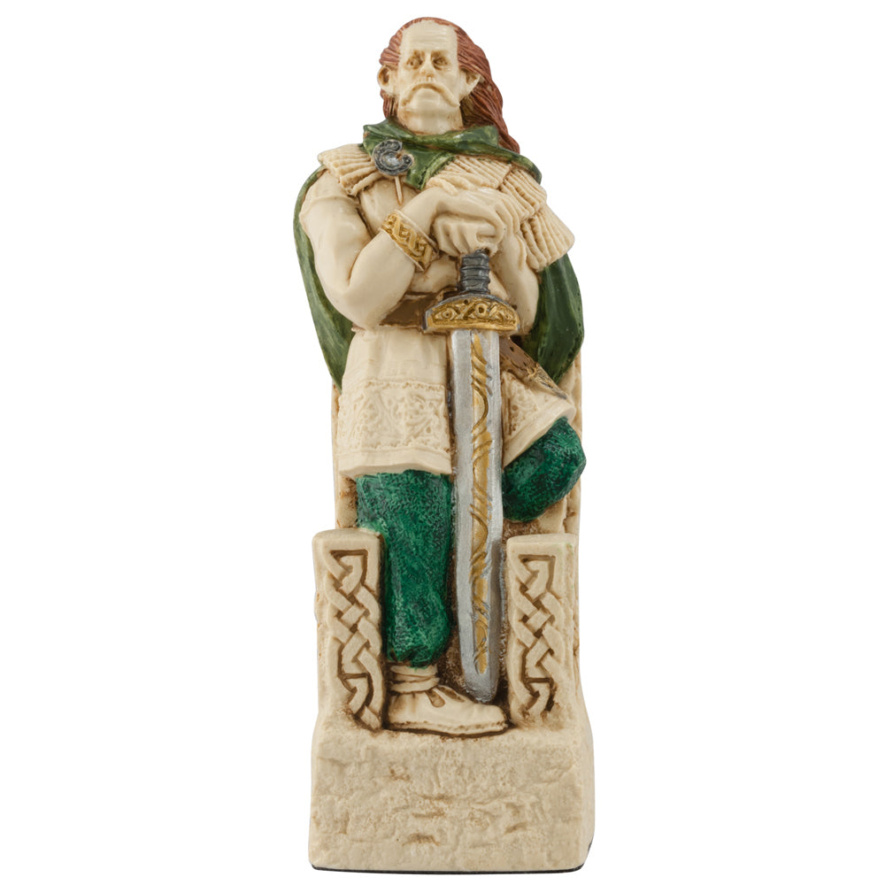 The Studio Anne Carlton Games Celtic & Viking Hand-painted Chess Pieces Set features a bearded man with long hair in a green cape and tunic, seated on a Celtic throne holding a downward sword—a unique addition for chess collectors.