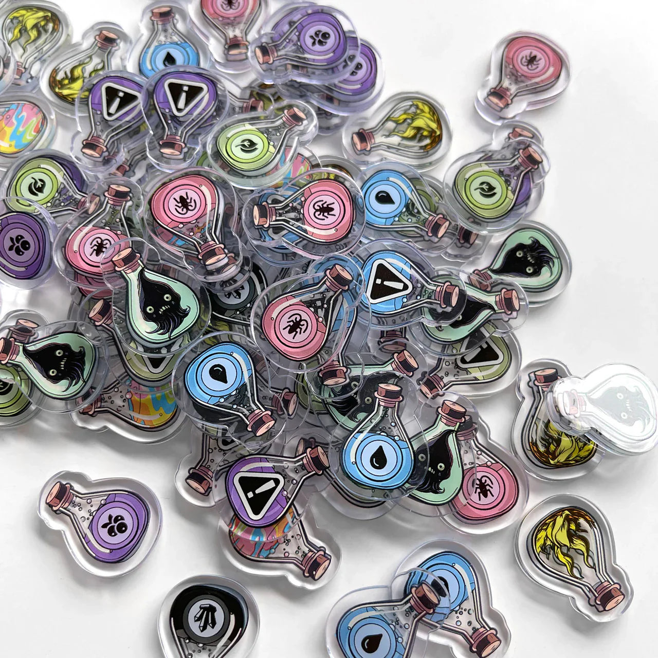 The Apothebakery Bundle by Lux Lupo features colorful acrylic potion bottle charms inspired by magical elixirs, decorated with eyes, paws, and warnings in pastel hues—perfect for any culinary alchemist.