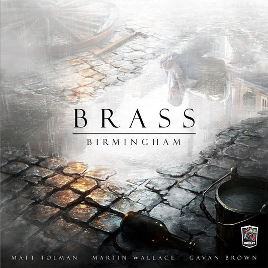The cover of Brass: Birmingham by Roxley Games features misty, wet cobblestone streets with a toppled bottle and bucket. The title is centered, while the creators' names and the Roxley Games logo are displayed at the bottom.