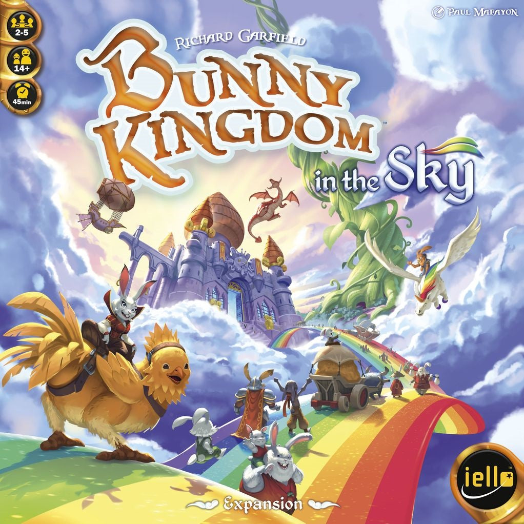 The Bunny Kingdom: In the Sky Expansion by Iello features colorful cover art with rabbits on a rainbow road among castles, floating islands, airships, and chicken riders in a fantasy sky kingdom. Brand and designer names appear on the cover.