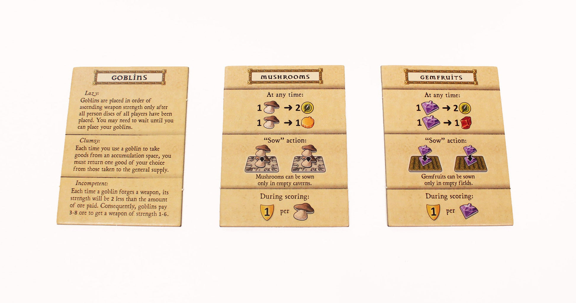 Three cards from Lookout Games’ Caverna: The Forgotten Folk Expansion—Goblins, Mushrooms, and Gemfruits—feature distinct rules and icons for actions and scoring, displayed side by side on a white background.