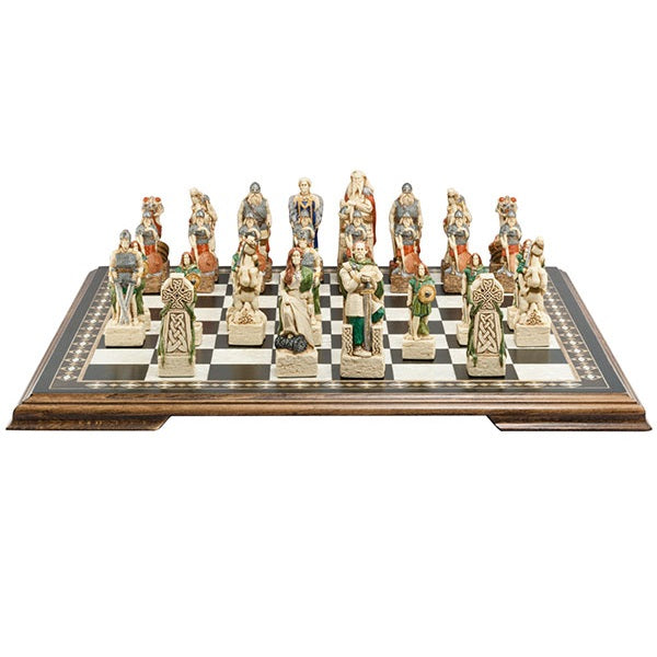 The Studio Anne Carlton Games Celtic & Viking Hand-painted Chess Pieces Set features intricately carved medieval-themed figures on a black and white chessboard with wooden border, bringing elegance and detail to any display.
