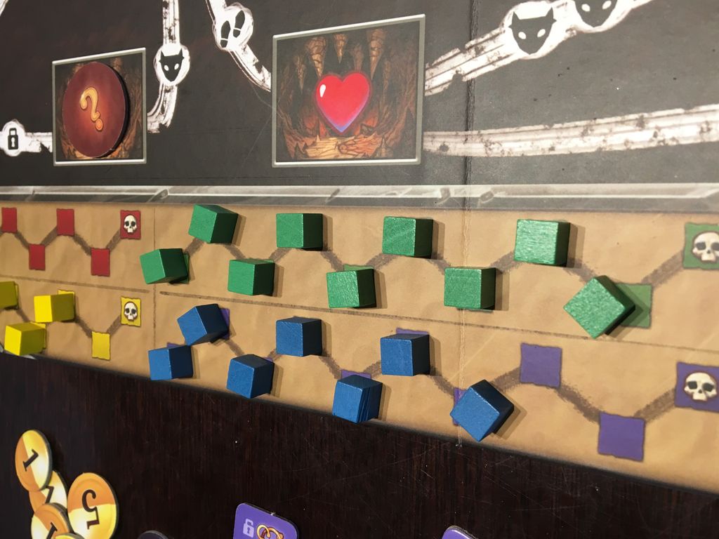 A close-up of Clank!: A Deck-Building Adventure by Renegade Game Studios, showing green, blue, and yellow cubes on a grid with tracks and symbols like a heart and question mark, hinting at adventure in the dragon’s lair.