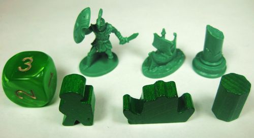 Several green game pieces from Matagot’s Cyclades are shown: a six-sided die (numbers 2 and 3 visible), a knight, a ship, a column, a meeple, a castle, and a cylindrical token.