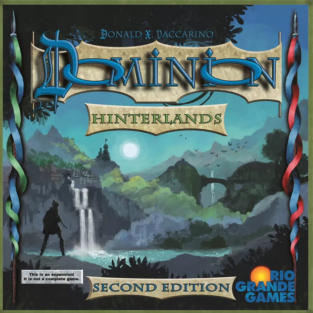 The box cover for Dominion: Hinterlands Expansion (Second Edition) by Rio Grande Games shows a fantasy landscape with a river, waterfalls, bridges, and a traveler's silhouette. The Rio Grande Games logo is in the bottom right corner.