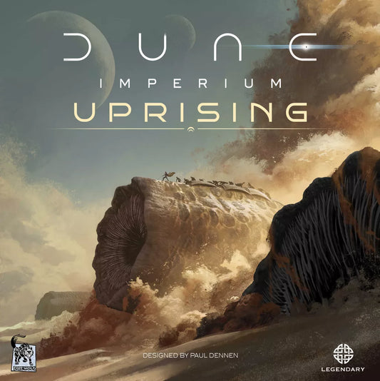 A giant sandworm rises under a dramatic sky as small figures stand on its back. The text "Dune: Imperium Uprising" by Dire Wolf appears, hinting at exciting deck-building and worker placement; logos are in the corners.