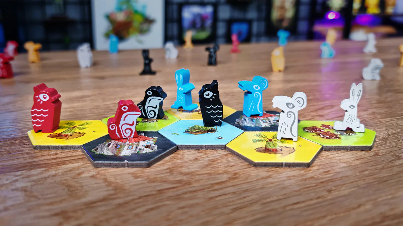 Animal-shaped pieces, like birds and mice, stand on hex tiles in Emberleaf by The City of Games. More animal pieces are blurred in the background on a wooden table, highlighting this engaging tile-placement game.