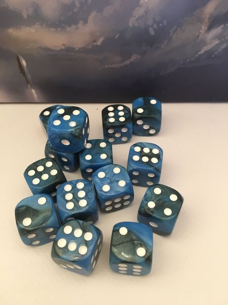 Thirteen blue marbled dice for Empires of the Void II by Red Raven Games are scattered on a white surface, set against a cloudy sky backdrop—perfect for enhancing your next space strategy game.