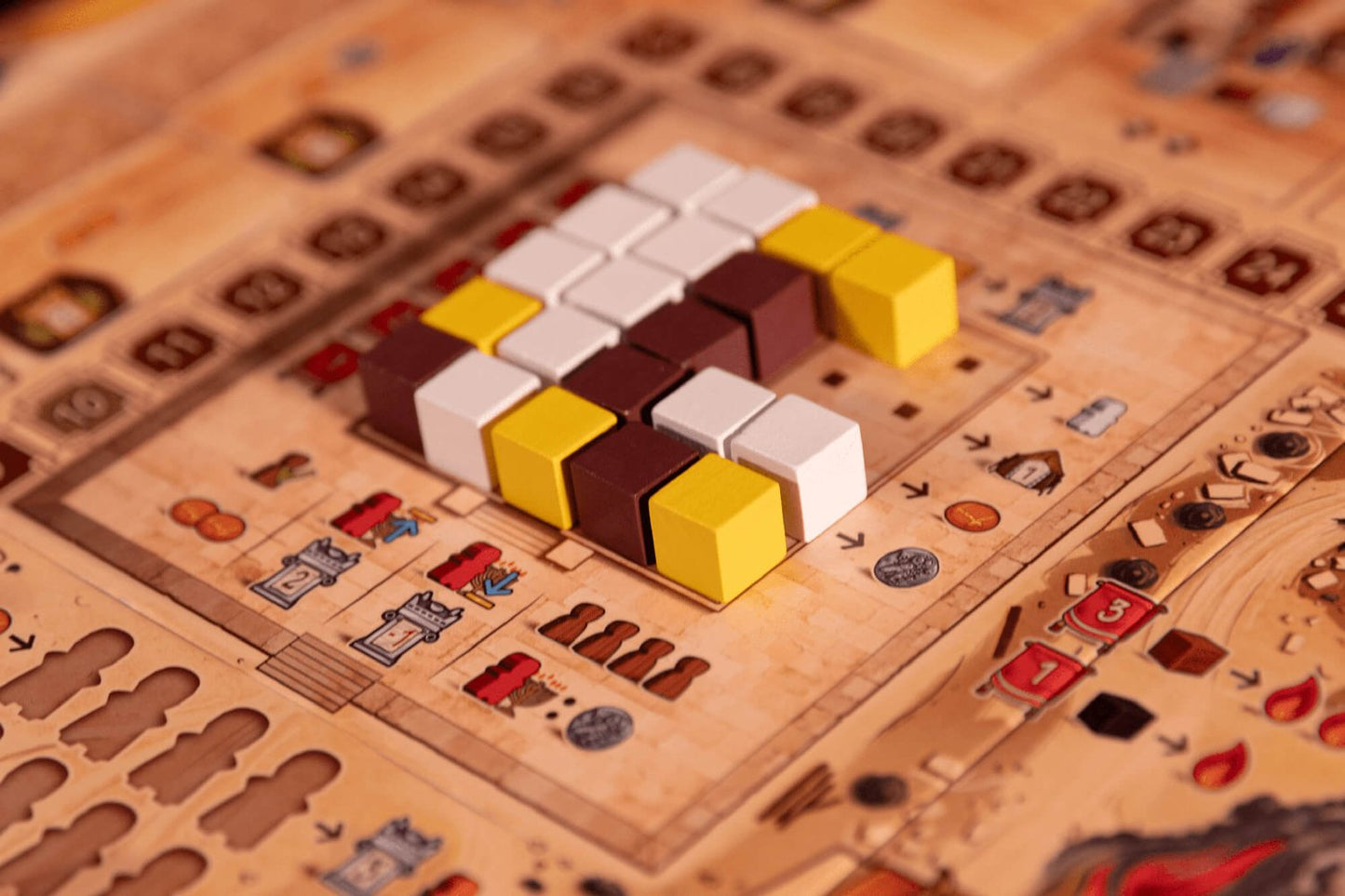 A close-up of Garphill Games' "Ezra and Nehemiah" board game shows white, yellow, and brown cubes on a grid with symbols and tracks inspired by the rebuilding of Jerusalem after Cyrus the Great’s decree.