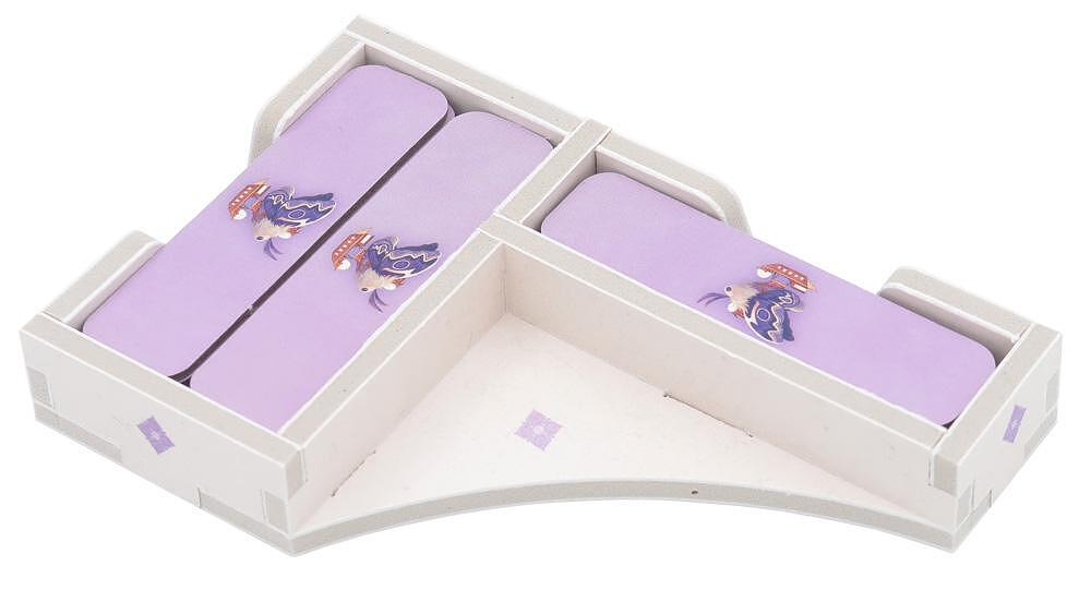 A small, L-shaped white sofa with purple cushions featuring cartoon bats and mushrooms adds a playful, minimalist touch—perfect for relaxing after organizing your board games with the Folded Space - Daitoshi Insert by Folded Space.