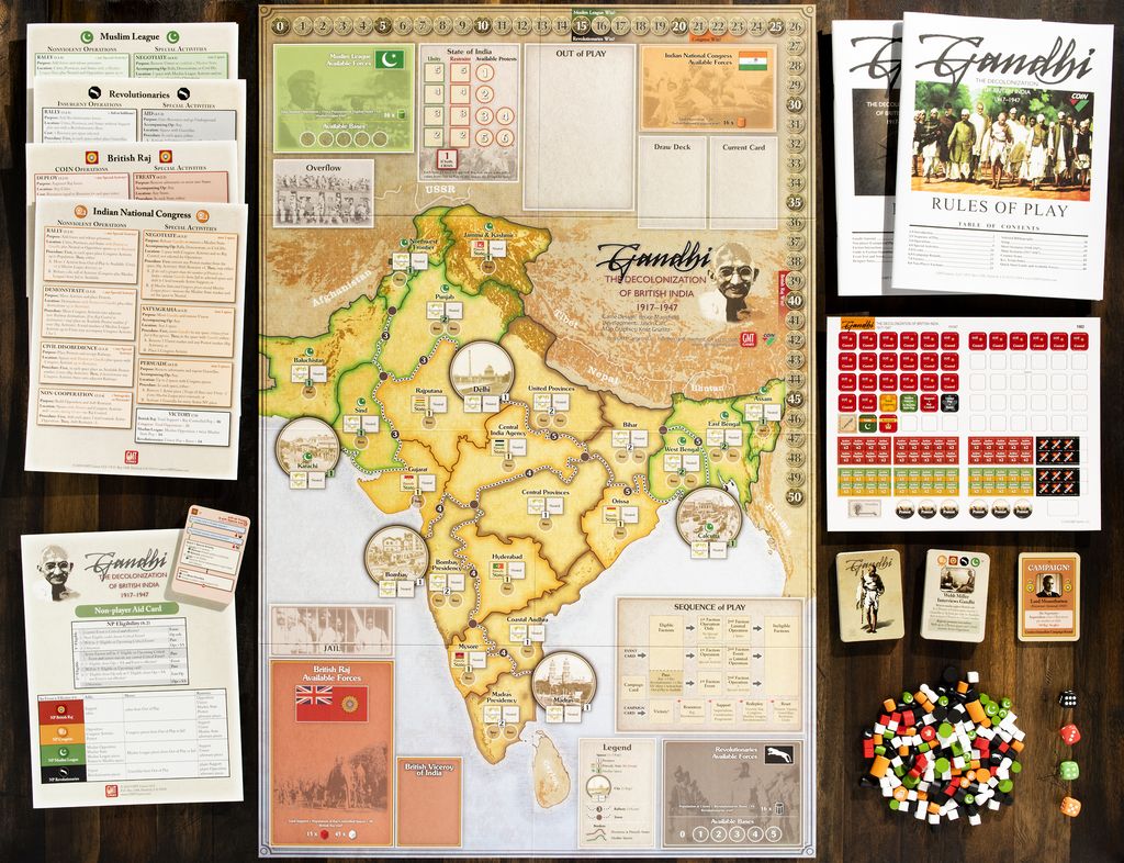 A setup for Gandhi: The Decolonization of British India, 1917–1947 by GMT Games showcases a detailed India map, player sheets, cards, tokens, wooden cubes, booklets, and score tracks from the COIN Series—all arranged on a table.