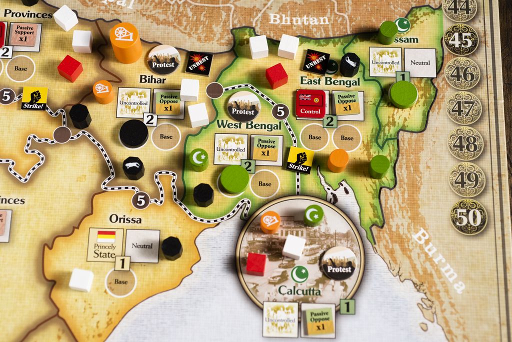 A close-up of the Gandhi: The Decolonization of British India, 1917 – 1947 board by GMT Games shows regions like West Bengal, Bihar, and Assam with colorful pieces representing nonviolent resistance and game actions.