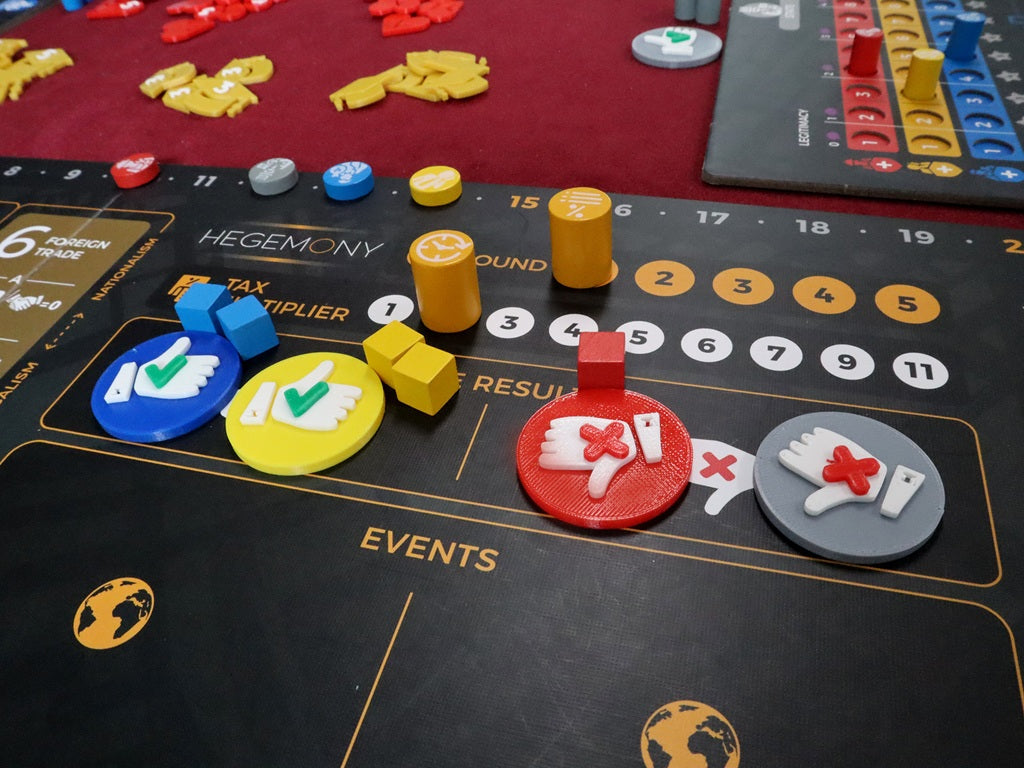 A close-up of Game Maker Team's Hegemony - 3D Upgraded Components shows vibrant tokens and markers on a black board with tax, events, and results sections featuring thumbs up/down icons. Additional 3D components are visible in the background.
