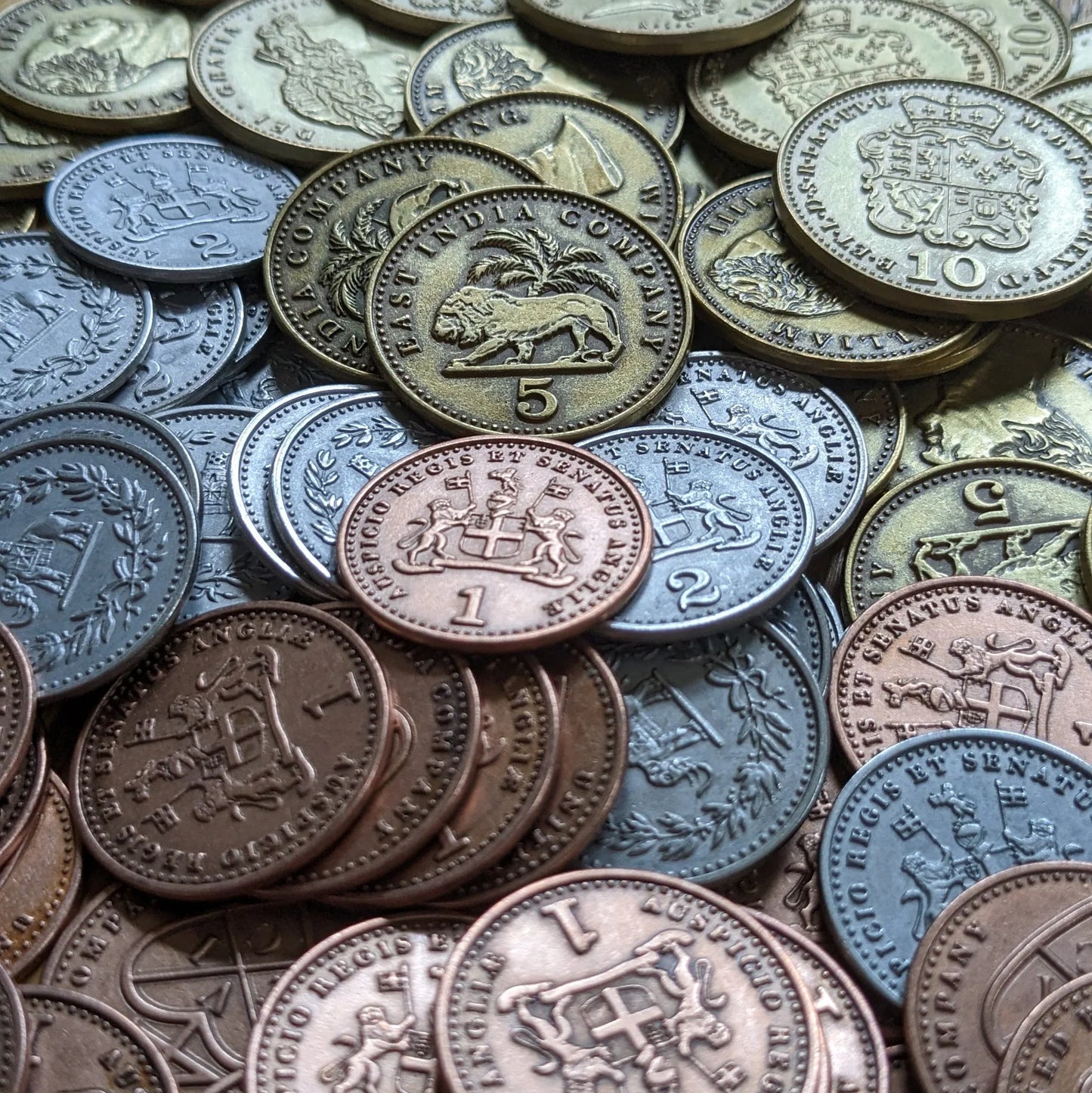 A detailed view of John Company Second Edition Metal Coins by Wehrlegig Games, showing bronze, silver, and gold coins with animal motifs, crests, and embossed numbers—ideal for enhancing your gameplay experience.