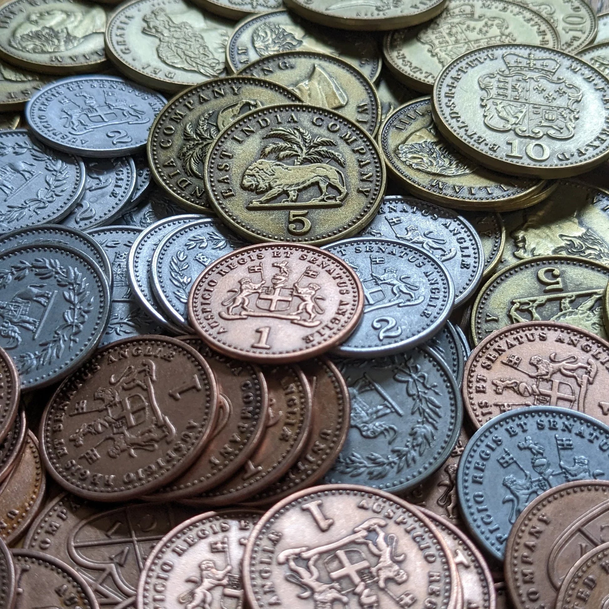A detailed view of John Company Second Edition Metal Coins by Wehrlegig Games, showing bronze, silver, and gold coins with animal motifs, crests, and embossed numbers—ideal for enhancing your gameplay experience.