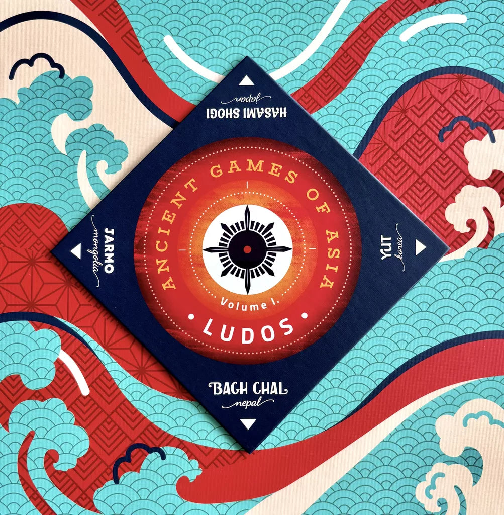 A square box of Ludos: Ancient Games of Asia by Lemery Games rests on a colorful background with stylized waves and red patterns, featuring traditional games from Japan, India, and Nepal: Hasami Shogi, Jut, Pachisi, and Bagh Chal.