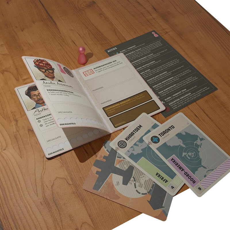 A Z-Man Games Pandemic Legacy Seizoen 0 NL setup on a wooden table includes a passport-style booklet, cards for Khartoum, Toronto, and North America, a pink game token, and a reference card with rules.