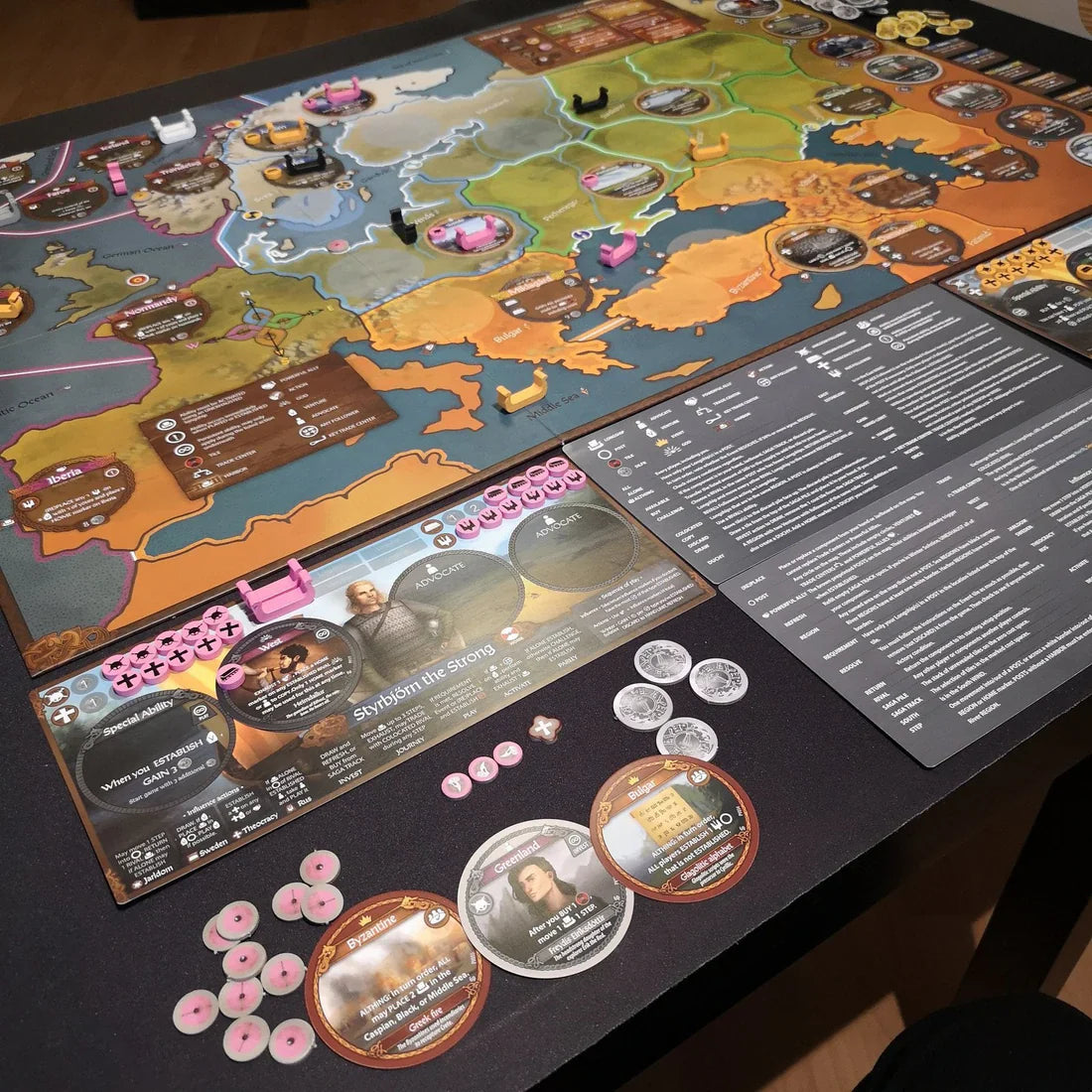 A close-up of Pax Viking by Ion Game Design, featuring a vibrant game board, tokens, cards, character boards, and reference sheets set on a table, all evoking the rich atmosphere of ancient Viking times.