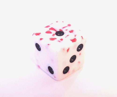 A white die with black dots and red speckles from Plague Inc. by Ndemic Creation is displayed on a plain white background.