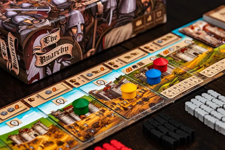 A close-up of The Anarchy, a medieval strategy game from Renegade Game Studios, shows colorful round player tokens on illustrated cards, black, red, and white resource tokens, and a detailed game box with medieval knights in the background.