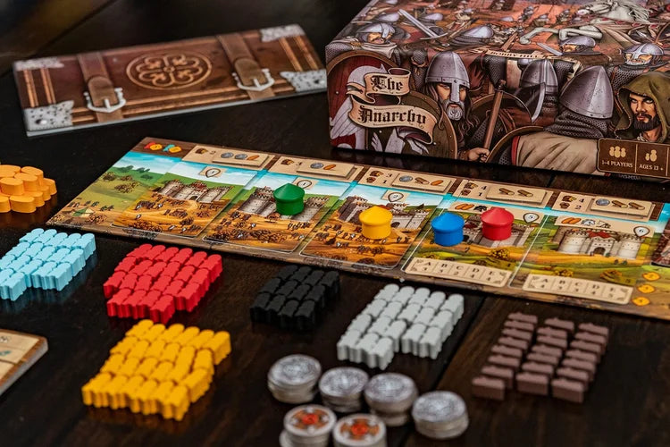 A close-up of The Anarchy by Renegade Game Studios, a medieval strategy board game with colorful wooden pieces, tokens, cards, and a castle-themed board. The box features armored knights and the game’s title.