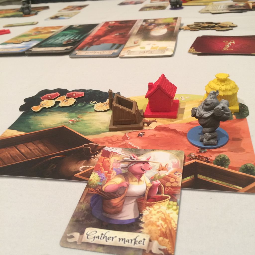 The Grimm Forest by Lucky Duck Games is a fairy tale board game featuring cards, tokens, wooden house pieces, and a gray animal figurine. Up front, the Gather Market card shows an illustrated pig in this whimsical house-building competition.