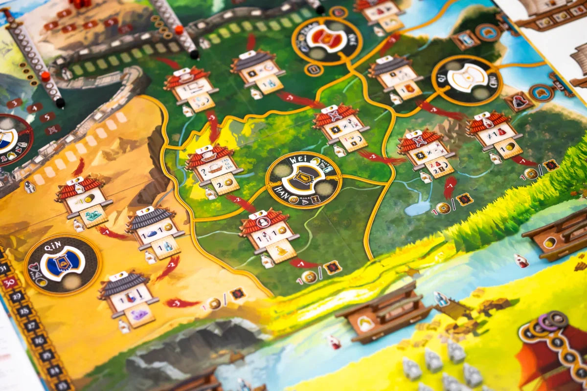 A colorful close-up of Tianxia by Board & Dice, a strategy board game set in the Warring States period, showcasing illustrated buildings, winding paths, diverse regions, and tokens on a vibrant map with green, yellow, and blue areas.