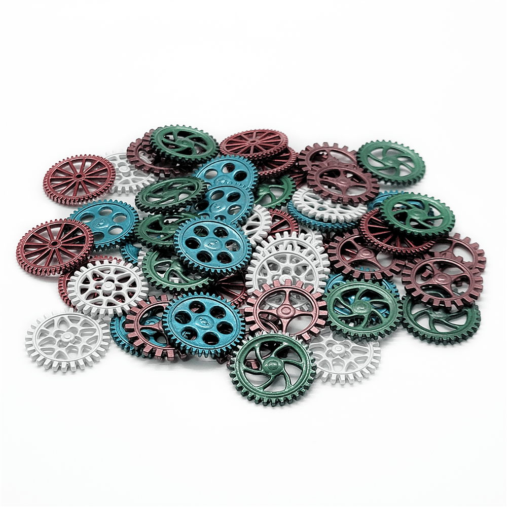 A pile of Weather Machine Metal Machine Parts by Eagle-Gryphon Games in green, red, and silver lies scattered on a white background. The assorted gears vary in size and design, with some having spokes and others solid centers.