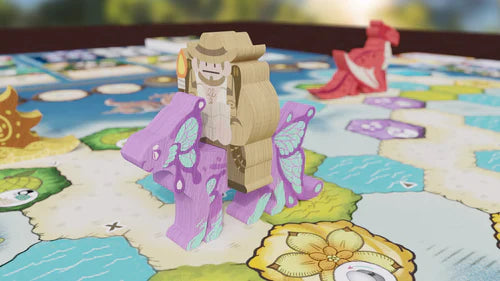 A wooden explorer game piece from Bad Comet's Wondrous Creatures: Crew Set Expansion rides a purple butterfly token on a hex-tiled, flower-filled map, with a red animal token in the background.