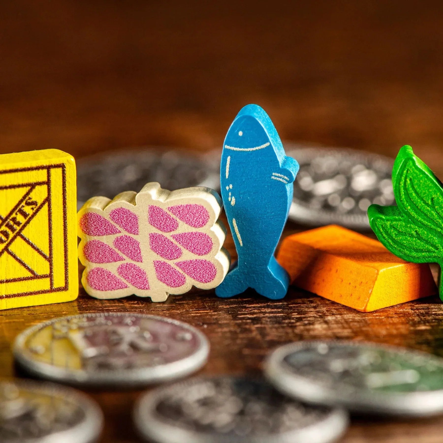 Enhance your Yokohama game with Synapses Games' Yokohama: Premium Tokens—a set of colorful wooden pieces shaped like a crate, fish, leaf, and cheese, plus silver coins—perfect for stylish board gaming!.