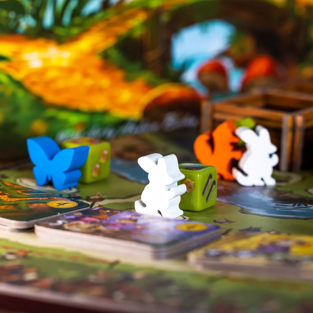 Colorful animal game pieces, dice, and cards are set on a vibrant, nature-themed My Lil' Everdell board by Starling Games (II), featuring blue butterfly, orange squirrel, and white mouse figures for kids.