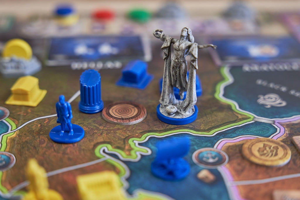 Board game with miniature figures and colorful pieces on a map