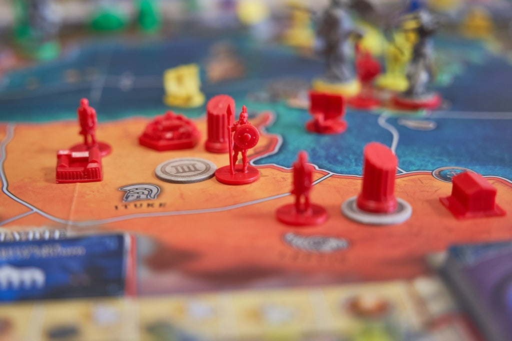 Board game with red player pieces on a colorful map
