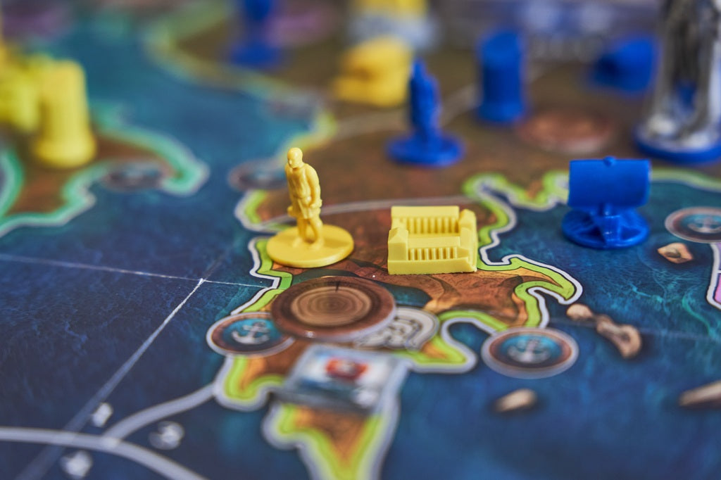 Board game pieces on a board with a focus on a yellow figure and building block.