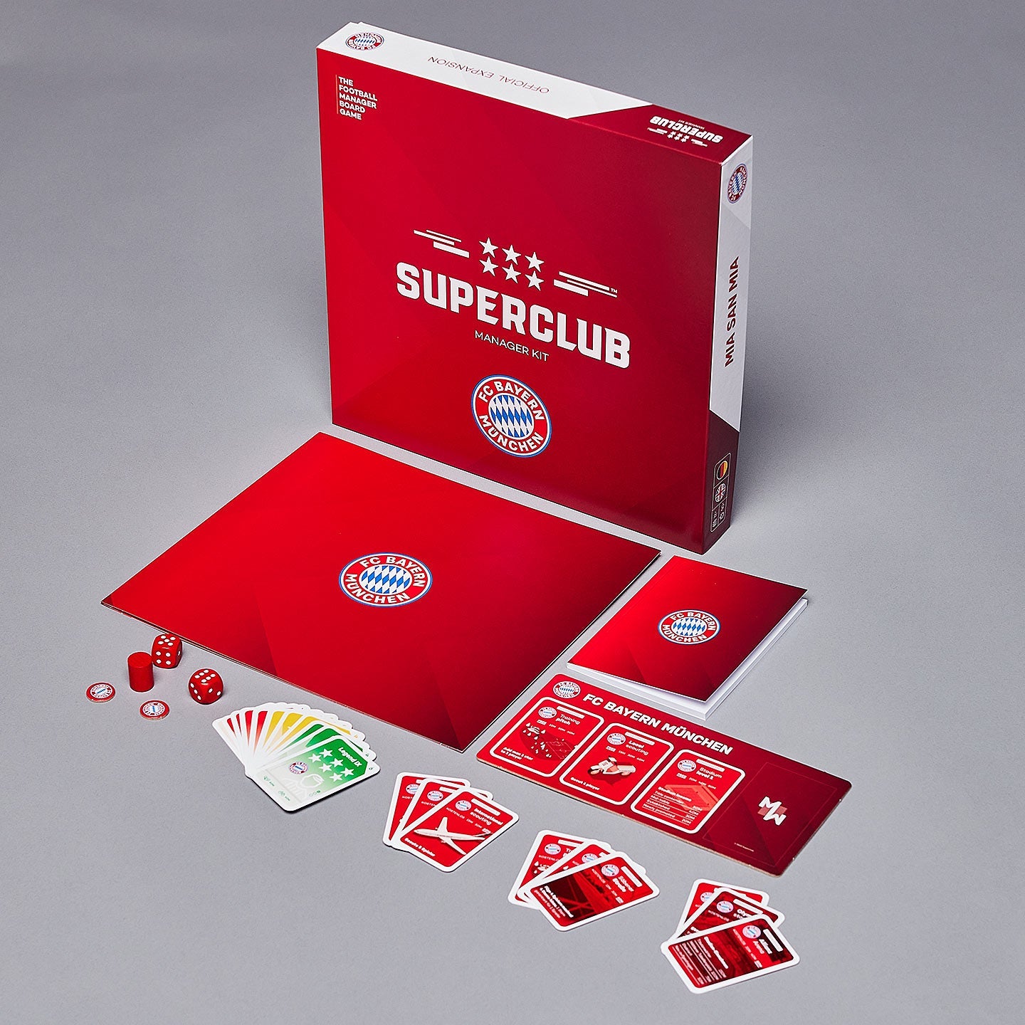 Superclub: Bayern München Manager Kit by Superclub—includes game box, dice, cards, player boards, and booklets in red with official club branding—arranged on a gray surface; ideal for European football fans.