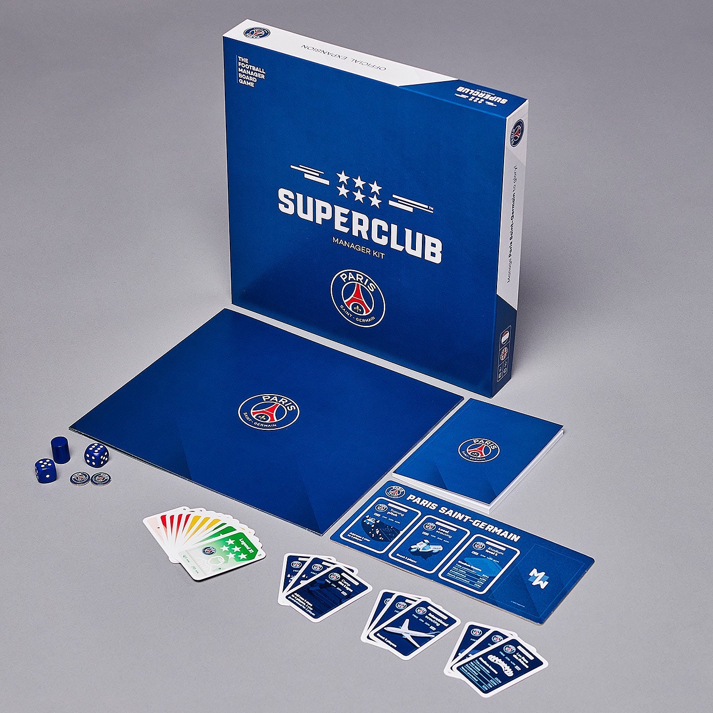 A photo of the Superclub: PSG Manager Kit by Superclub, showing its blue box, game board, dice, cards, and pieces arranged on a gray surface—ideal for any Paris Saint-Germain fan or aspiring football manager.