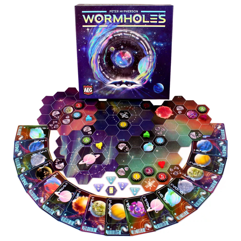Wormholes by Alderac Entertainment Group is a colorful pick-up-and-deliver game featuring hexagonal space tiles, planet cards, spaceship tokens, and game pieces arranged in a semi-circle with the Wormholes box displayed in the background.